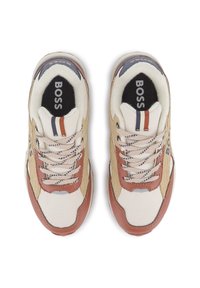 Ténis desportivos bege e castanhos, com materiais em malha e camurça, atacadores e um logo impresso. O design apresenta riscas de várias cores no calcanhar.