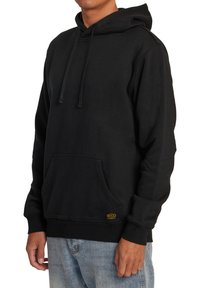 Hoodie noir en coton mélangé, avec une poche kangourou, capuche à cordon et poignets côtelés. Petit logo jaune en détail à l'ourlet.