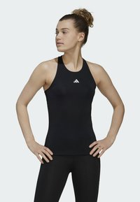 Fekete sportos ujjatlan felső, rugalmas anyagból készült, magas nyakkivágással és fehér Adidas logóval. Sima textúra, testhez simuló dizájn.