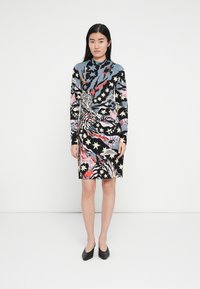 Dlhý pletený šaty s dlhými rukávmi, čiernym pozadím s farebnými zvieracími a hviezdnymi vzormi, vysokým golierom a priliehavým strihom.