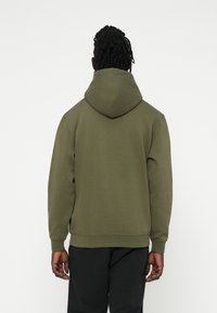Olivovo zelená mikina z mäkkého materiálu s veľkou kapucňou, rebrovanými manžetami a voľným strihom, s minimalistickými dizajnovými detailmi.