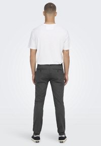 Grå byxor med rak passform, två bakfickor, tillsammans med en enkel vit t-shirt. Tyget verkar slätt och lätt.
