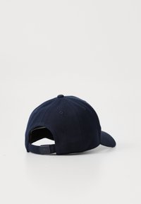 Casquette de baseball bleu marine en tissu texturé, avec une visière courbée et une sangle ajustable à l'arrière. Comprend des trous de ventilation et un doublage lisse.