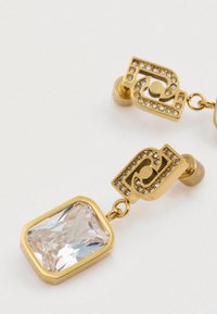 Χρυσά σκουλαρίκια με ένα διάφανο ορθογώνιο πέτρωμα, διακοσμημένα με γεωμετρικό σχέδιο που περιλαμβάνει μικρούς διαφανούς κρυστάλλους κατά μήκος της κορυφής.