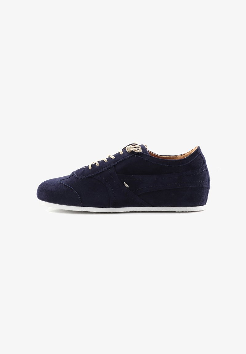 Navy suede athletic shoe with beige laces, low profile, rounded toe, and white rubber sole. Features stitched accents and minimal detailing.