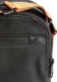 Borsa di stoffa nera con una tracolla arancione, caratterizzata da una texture liscia, una tasca frontale con zip e accessori in plastica.