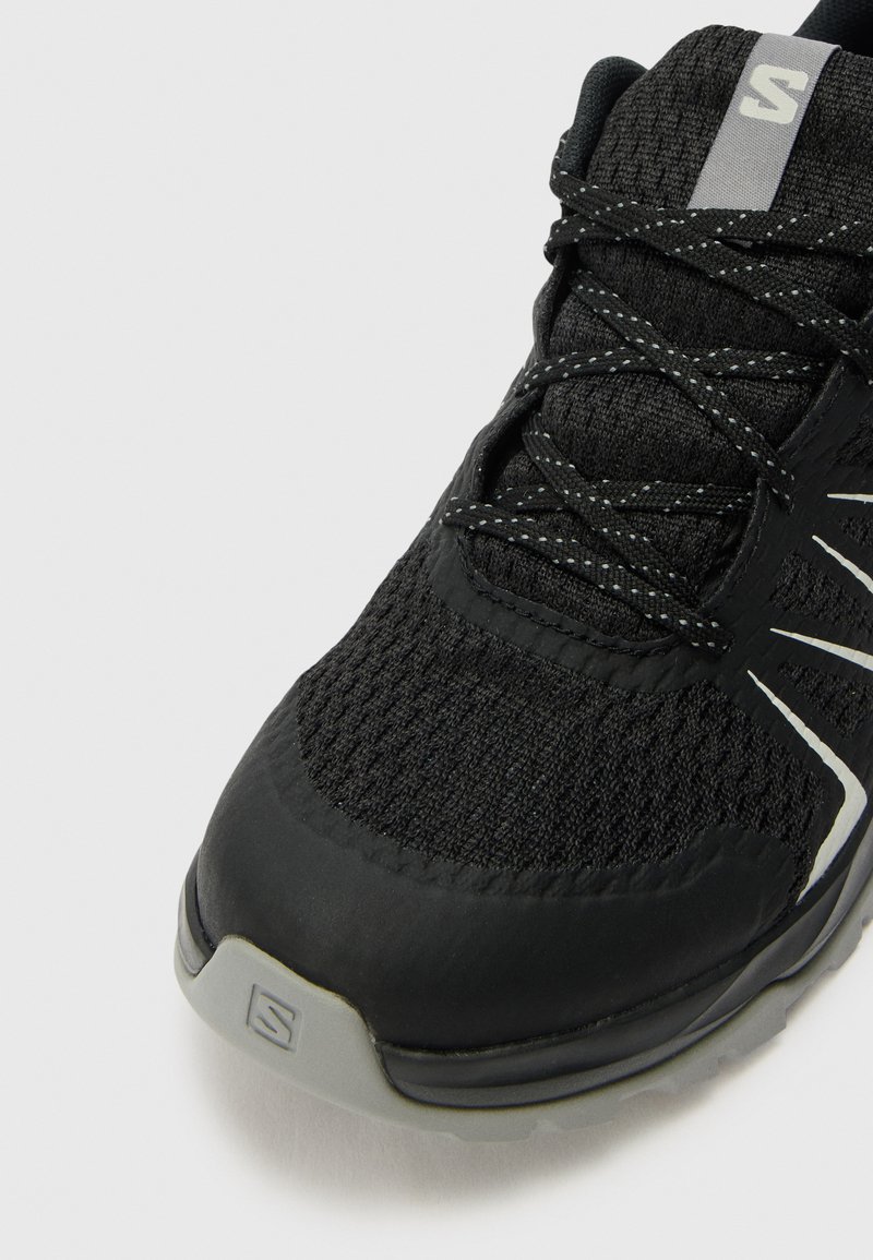 Schwarzer Sportschuh mit einem Obermaterial aus Netzgewebe und synthetischen Akzenten. Verfügt über reflektierende Details, eine strukturierte Oberfläche und eine gepolsterte Sohle.