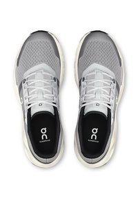 Pelēki sporta apavi ar sieta augšdaļu, baltām auklām un gludu tekstūru. Iespējas ietver logotipu un zīmola nosaukumu uz zolēm. Noapaļota forma, viegla konstrukcija.