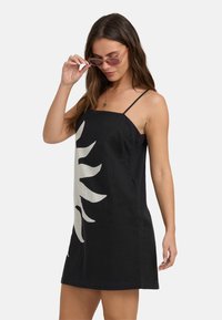 Zwarte linnen jurk met witte zonafbeelding, spaghettibandjes en een ontspannen fit, die een gladde textuur en minimalistisch ontwerp laat zien.