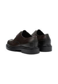 Pantofi din piele maro, cu vârful rotunjit, design cu șireturi și talpă groasă neagră. Textură netedă, cu detalii de cusătură subtile.