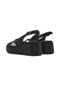Zwarte leren platform sandalen met open teen, uitsparingen aan de zijkanten, verstelbare enkelriem en gestructureerde wiggenhak. Gladde afwerking.