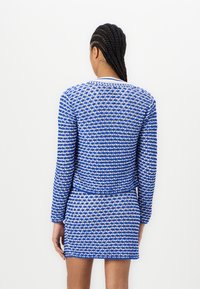 Sininen ja valkoinen kuvioitu kaksiosainen asu, jossa on pitkähihaisena paita ja tiukka mini-hame, teksturoitu kangas, pyöreä kaula-aukko ja slim fit.