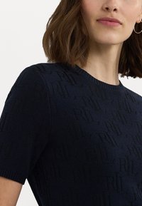 Ναυτικό μπλε πλεκτό πουλόβερ με κοντά μανίκια, που διαθέτει υφή με το μοτίβο των γραμμάτων 'R' και 'L'. Στρογγυλή λαιμόκοψη με ριμπ επένδυση.