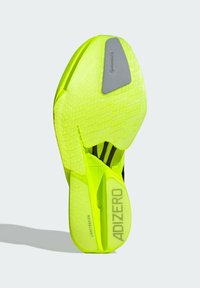 Podrážka topánky v jasne neonovo žltej gumene s textúrovaným protišmykovým vzorom, s logom v striebornom tóne a značkou "ADIZERO".