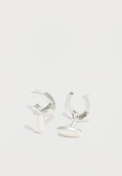 Ζευγάρι γυαλισμένων ασημένιων μανικετόκουμπων με κυρτούς U-σχήματος μπάρες και χαραγμένα οβάλ πρόσωπα σε λευκό φόντο.