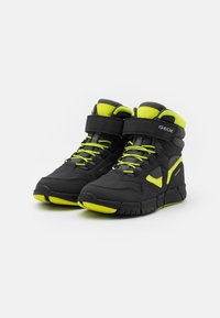 Schwarze High-Top-Sneaker mit neongrünen Akzenten, ausgestattet mit einem strukturierten Obermaterial, Schnürsenkeln, einem Klettverschluss und einem robusten Laufsohlen-Design.