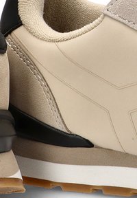 Zapatillas deportivas beige con materiales de ante y sintéticos. Presentan una suela texturizada, detalles en negro y un minimalismo en las costuras.