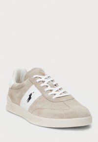 Sneaker in suede beige chiaro con dettagli bianchi, design con lacci, punta rotonda e una patch con logo sul lato; tomaia testurizzata e suola liscia.