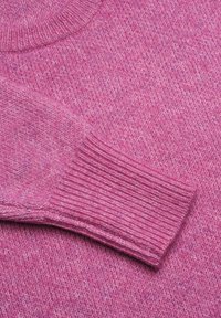 Texturerad rosa tröja med rund halsringning och ribbade ärmslut; garnet har ett subtilt melerat mönster för extra djup.