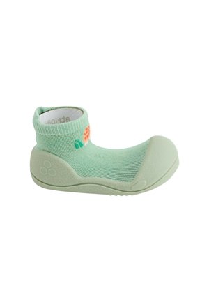 Scarpa morbida verde per bambino con tomaia tipo calzino e suola e punta in gomma protettiva, con piccolo disegno arancione e verde sul lato.