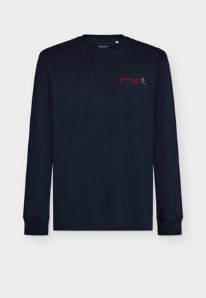 Ναυτικό μπλούζα με μακριά μανίκια φτιαγμένη από βαμβάκι, με στρογγυλή λαιμόκοψη, ριμπ μανσέτες και κόκκινες κεντητές επιγραφές στο στήθος.