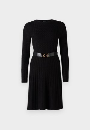 Schwarzes Strickkleid mit langen Ärmeln und geripptem Muster. Hat ein enges Oberteil und einen ausgestellt Rock, der in der Taille mit einem schwarzen Gürtel und einer goldenen Schnalle gerafft ist.