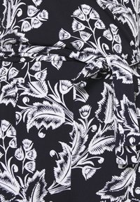 Black fabric with white floral pattern and a tied belt detail.