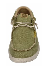 Scarpa in tessuto verde con punta arrotondata, accenti beige e superficie testurizzata. Presenta cuciture decorative e lacci elastici.
