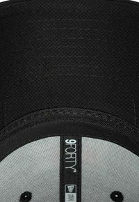 Schwarze Baseballkappe mit strukturiertem Design, grauer Unterseite und einem Etikett mit der Aufschrift „9FORTY“ auf dem Vorderteil.