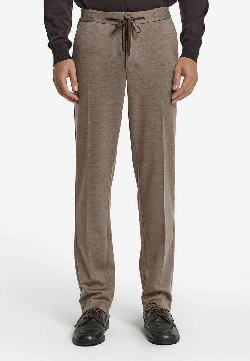 Jasnobrązowe spodnie o miękkim, teksturowanym wykończeniu. Posiadają elastyczny pas z troczkami oraz boczne kieszenie. Połączone z czarnymi butami.