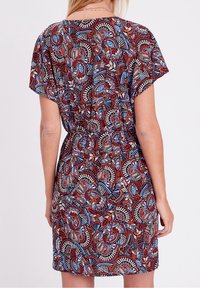 Robe à manches courtes présentant un motif multicolore floral et géométrique en rouge, bleu et blanc. Taille élastique, coupe décontractée, tissu léger.