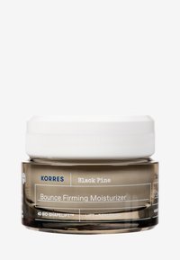 Korres Black Pine Bounce Firming Moisturizer i en transparent glasburk med ett vitt skruvlock, med blå och vita textetiketter.