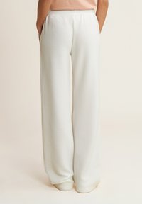 Pantaloni a gamba larga in tessuto bianco testurizzato, con vita elastica e tasche laterali. Linee pulite e vestibilità rilassata.