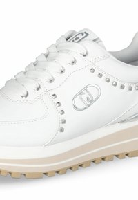 Sneakers bianchi con tomaia in pelle testurizzata, dettagli in argento e borchie a piramide. Presentano una suola beige spessa con scanalature per il grip.
