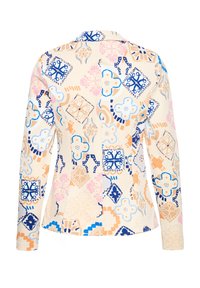 Blazer crème à manches longues avec motifs géométriques et floraux en bleu, beige et rose, présenté de dos sur un fond blanc.