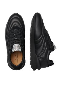Scarpe da ginnastica nere con un esterno in pelle liscia, sovrapposizioni testurizzate e una suola in gomma resistente. Caratteristiche includono lacci e accenti del logo.