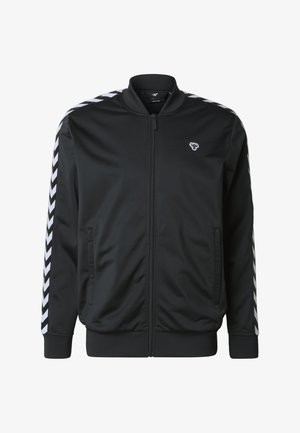 Zwarte bomberjack van gladde stof met een ritssluiting aan de voorkant en geribbelde manchetten. Voorzien van witte chevronstrepen langs de schouders.