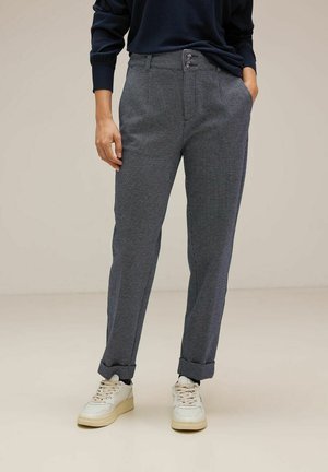 Pantaloni a quadri grigi con vestibilità slim. Presentano due bottoni in vita, tasche laterali e orli arrotolati. Abbinati a sneaker bianche.