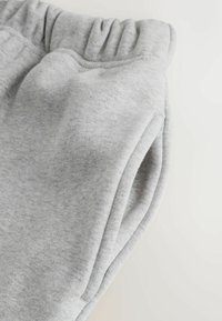 Light grey sweatpants with elastic waistband and side pocket, made of soft knit fabric on a plain light background.