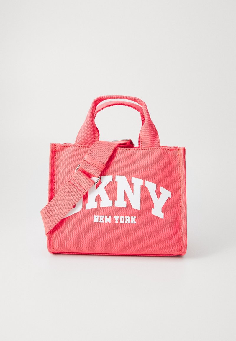 Petit sac cabas en toile rose avec poignées courtes et bandoulière réglable, avec inscription blanche « DKNY New York » sur le devant.
