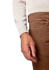Lichtbeige gebreide trui met geribbelde manchetten, gecombineerd met bruine corduroy broeken met zijzakken en een gestructureerd stofdetail.