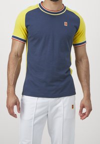 Námořnická a žlutá košile s krátkým rukávem, s texturovanou tkaninou, žebrovaným límečkem a červenými a modrými akcenty. Malé logo na hrudi.