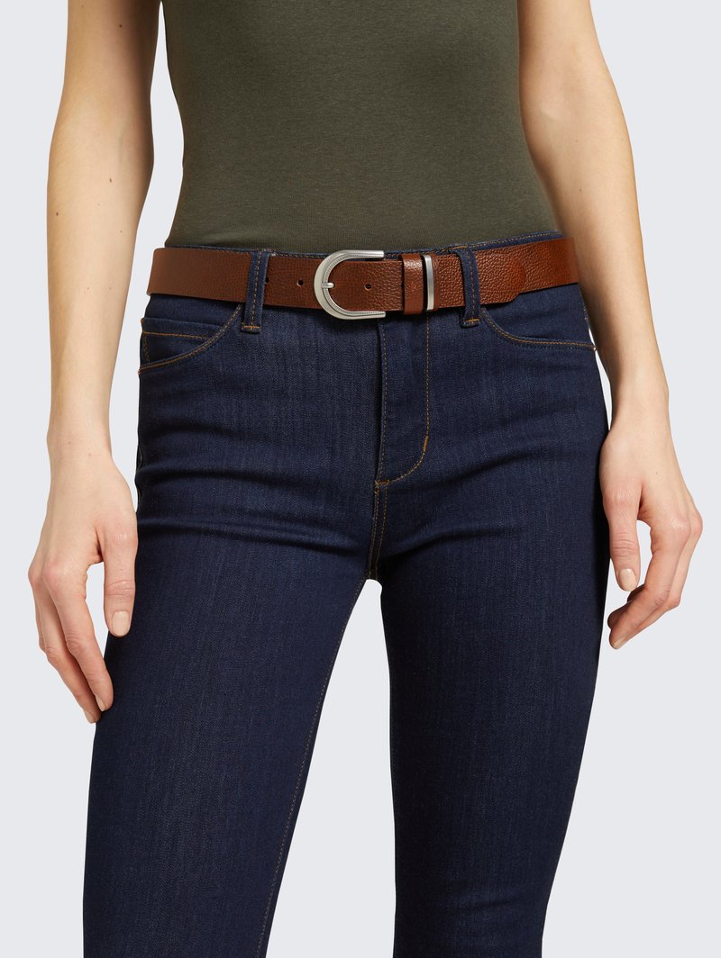 Brown leather belt with a textured finish, silver metal buckle, and adjustable holes, worn with dark blue denim jeans.