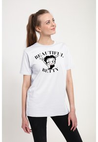 Camiseta de algodón blanca con un gráfico negro de un personaje de dibujos animados y el texto "BEAUTIFUL BETTY" en fuente negrita. Manga corta y cuello redondo.