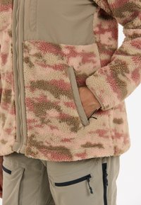Fleecejacka i rosa, beige och brun kamouflage-mönster med dragkedja fram, sidofickor och elastiska ärmslut. Har ett mjukt, slitstarkt tyg.