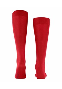 Calze rosse fino al ginocchio realizzate in tessuto morbido, con un bordo a coste e punta e tallone rinforzati. Design semplice senza pattern né decorazioni.
