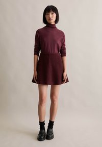 Bordowy golf połączony z rozkloszowaną, teksturowaną spódnicą. Czarne skarpety i masywne mokasyny dopełniają całość. Prosty, nowoczesny design.