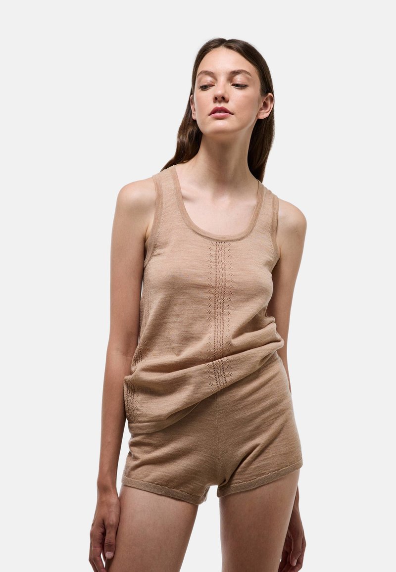 Débardeur en tricot beige à encolure ronde et shorts ajustés courts. Texture subtile, avec des détails de couture verticaux pour plus d'intérêt.