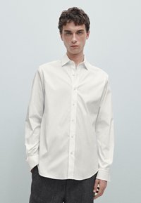 Camicia bianca con colletto aperto e maniche lunghe, dotata di una texture in cotone liscia e un design slim fit.