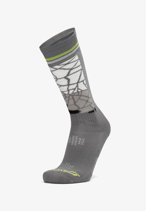 Graue Sportsocke mit einem weißen und schwarzen Spinnennetzmuster, einem limonengrünen Streifen nahe dem Bündchen sowie verstärkten Zehen- und Fersenbereichen.